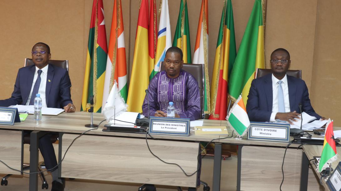 Propriété urbaine : L’UEMOA franchit un cap vers un cadre foncier unifié Les ministres en charge de l’Urbanisme, de l’Habitat, des Domaines et du Cadastre des États membres de l’Union économique et monétaire ouest-africaine (UEMOA) ont approuvé, le 26 juin 2026, un projet de directive communautaire visant à harmoniser les règles relatives à l’immatriculation foncière, à l’accès au titre de propriété et à la gestion des informations foncières en milieu urbain. Réunis sous la présidence de Mikaïlou Sidibé, les participants ont salué une avancée majeure dans la construction d’un cadre foncier commun au sein de l’Union. Selon le ministre burkinabè, cette directive contribuera à uniformiser les procédures foncières, à faciliter l’accès aux titres de propriété et à renforcer les systèmes d’information foncière, considérés comme des outils essentiels pour soutenir des politiques de logement inclusives et durables. Pour Jonas Gbian, la sécurisation de l’accès au foncier urbain constitue un enjeu stratégique pour le développement économique des États membres. Il a souligné que les difficultés liées à la sécurisation foncière continuent de freiner les investissements, l’aménagement du territoire et la réalisation de grands projets structurants dans plusieurs pays de l’Union. Face à ces défis communs, la Commission de l’UEMOA a élaboré cette directive afin de créer un cadre harmonisé encadrant l’immatriculation foncière, l’accès à la propriété et la mise en place de systèmes d’information foncière performants dans les zones urbaines. L’approbation du texte marque une étape importante vers l’instauration d’une gouvernance foncière plus cohérente à l’échelle régionale. La directive sera désormais soumise aux instances statutaires de l’UEMOA pour adoption définitive. Une fois entrée en vigueur, elle devrait contribuer à renforcer la sécurité juridique des transactions foncières, améliorer le climat des affaires et soutenir les politiques de développement urbain dans l’ensemble de l’Union.